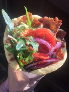 Vegan wrap with plant based gyros, rocket, tomatoes, onions