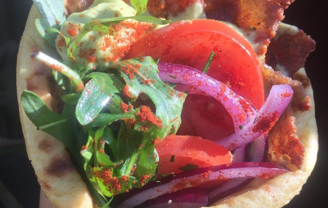 Vegan wrap with plant based gyros, rocket, tomatoes, onions