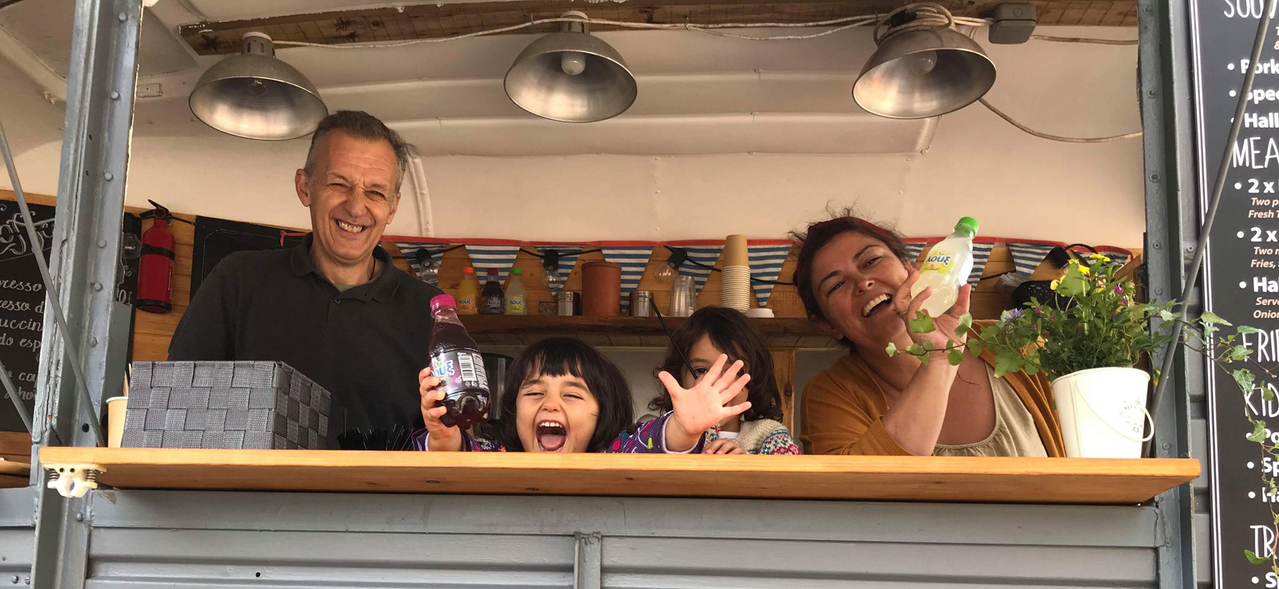 Staff and children in food truck, smiling